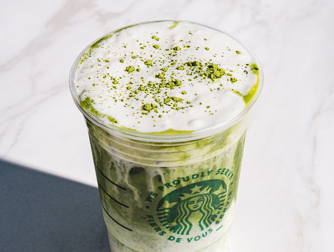 Close-up of a Iced Matcha Latte in a Starbucks cup under the runny patio table.
